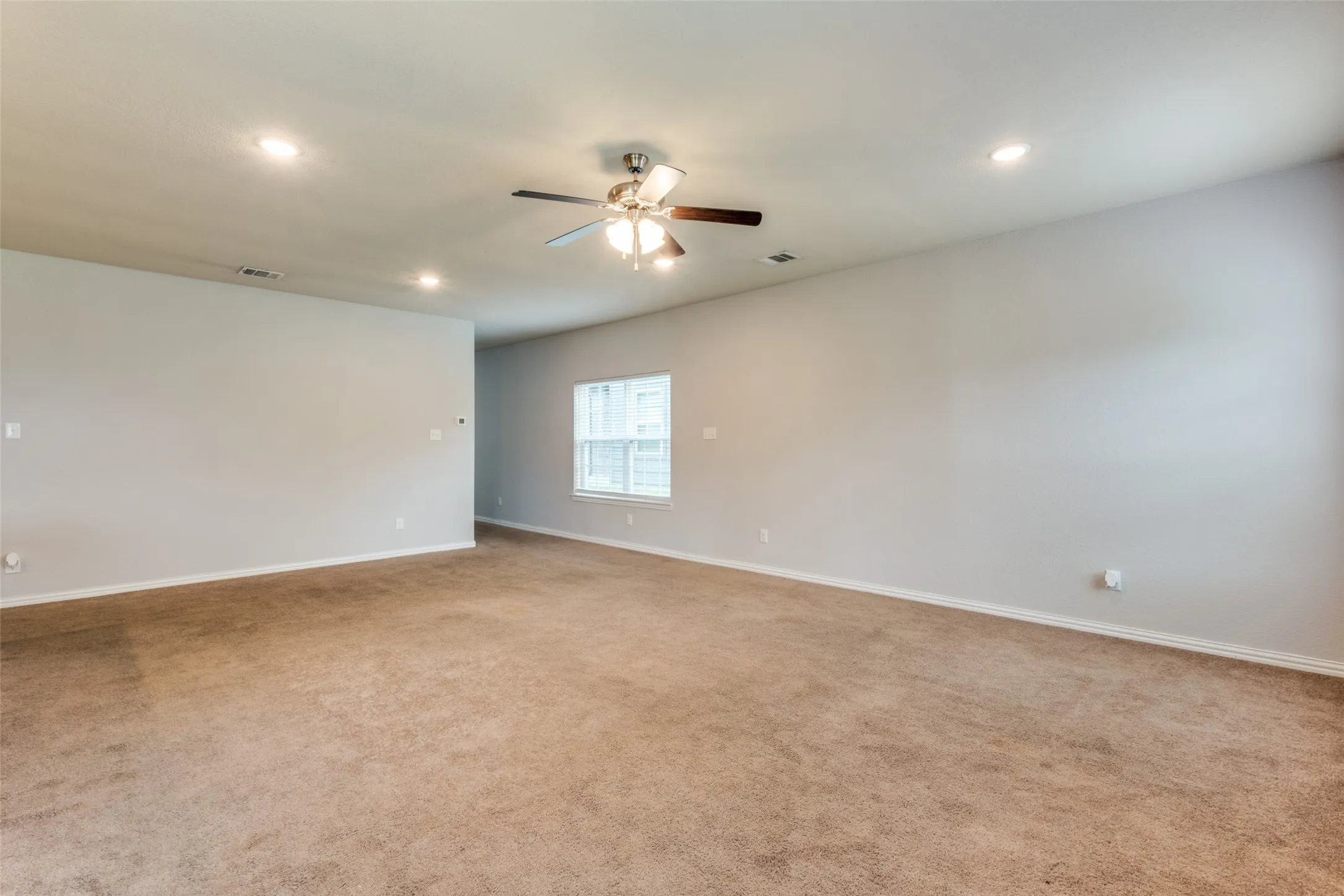 Spacious interior featuring neutral wall tones, wall-to-wall carpeting, recessed lighting, and a centrally mounted ceiling fan