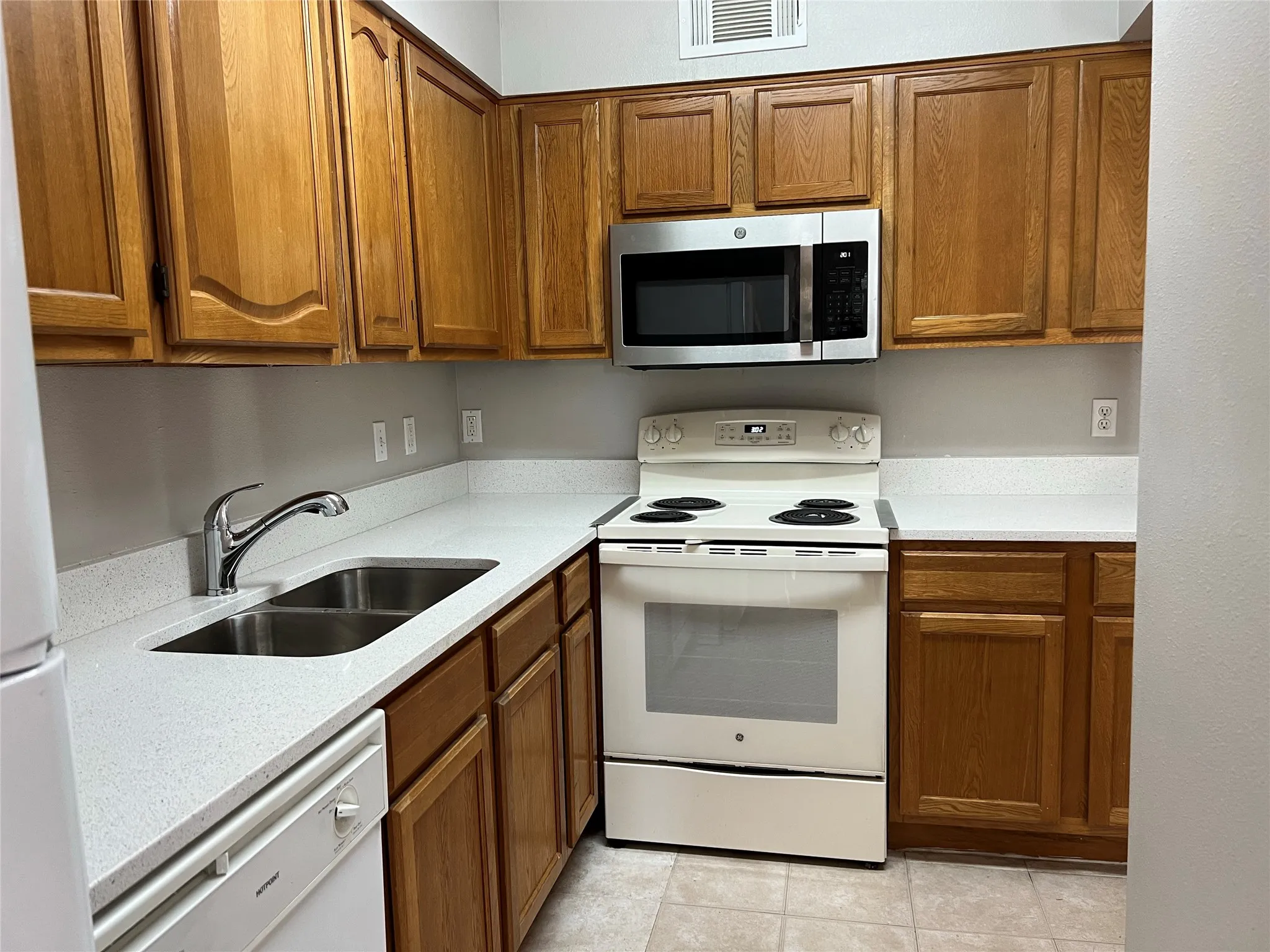 Kitchen featuring light tile floors, white appliances, and sink
