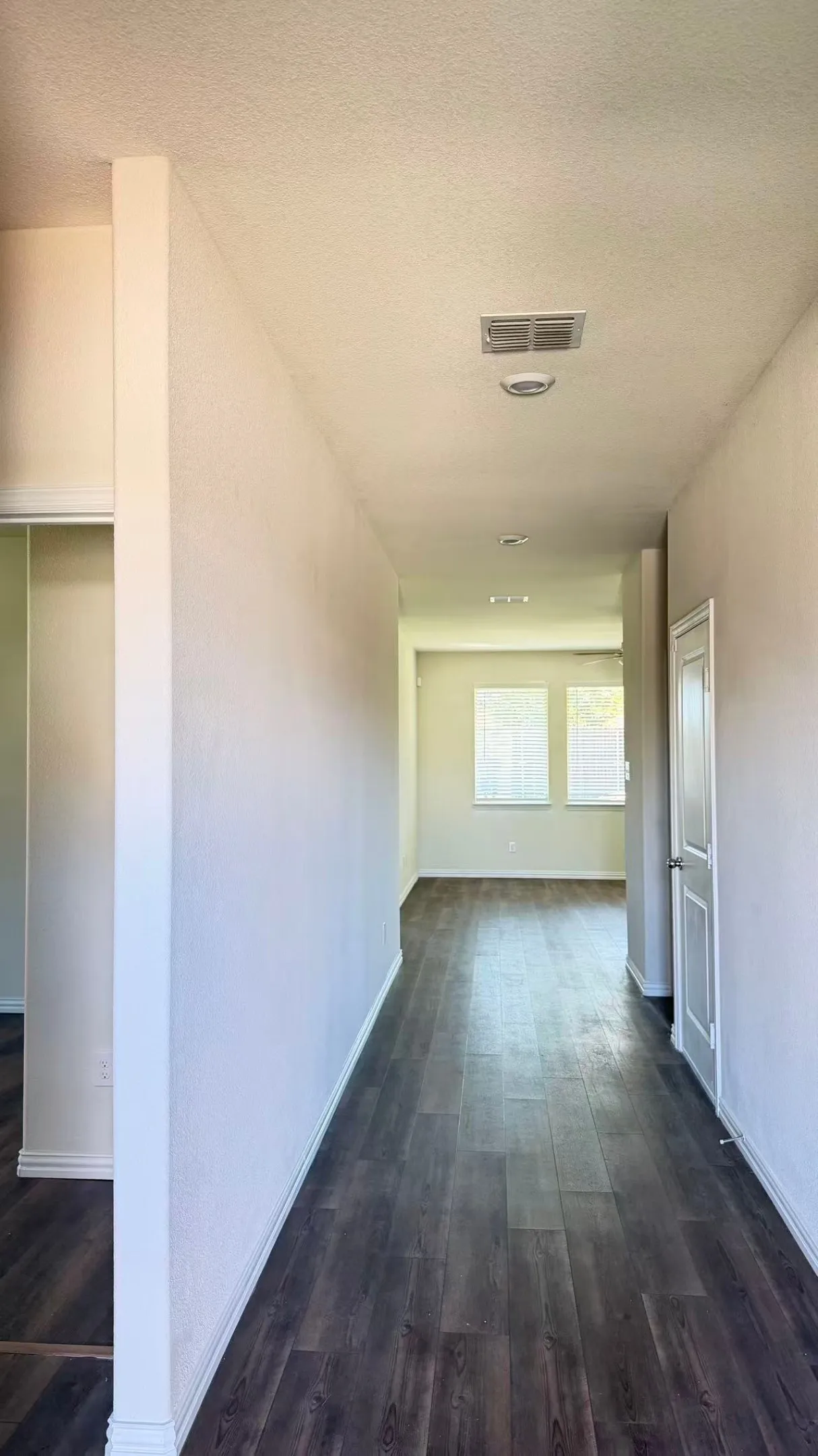 Neutral wall tones, wood-finish flooring, and recessed ceiling lighting, punctuated by paneled interior doors and dual window treatments