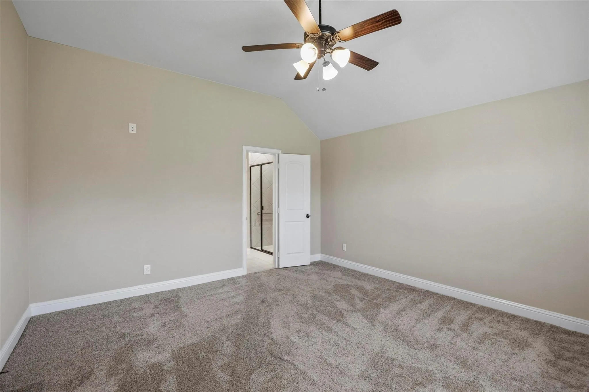 Vaulted ceiling, ceiling fan with light fixture, neutral wall color, and wall-to-wall carpeting