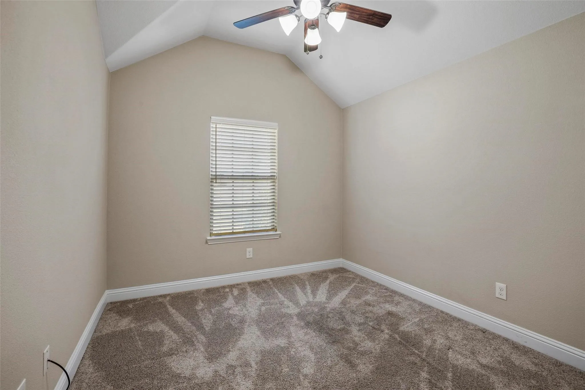 Room featuring a vaulted ceiling, neutral wall tones, neutral carpeting, and a ceiling fan with integrated lighting