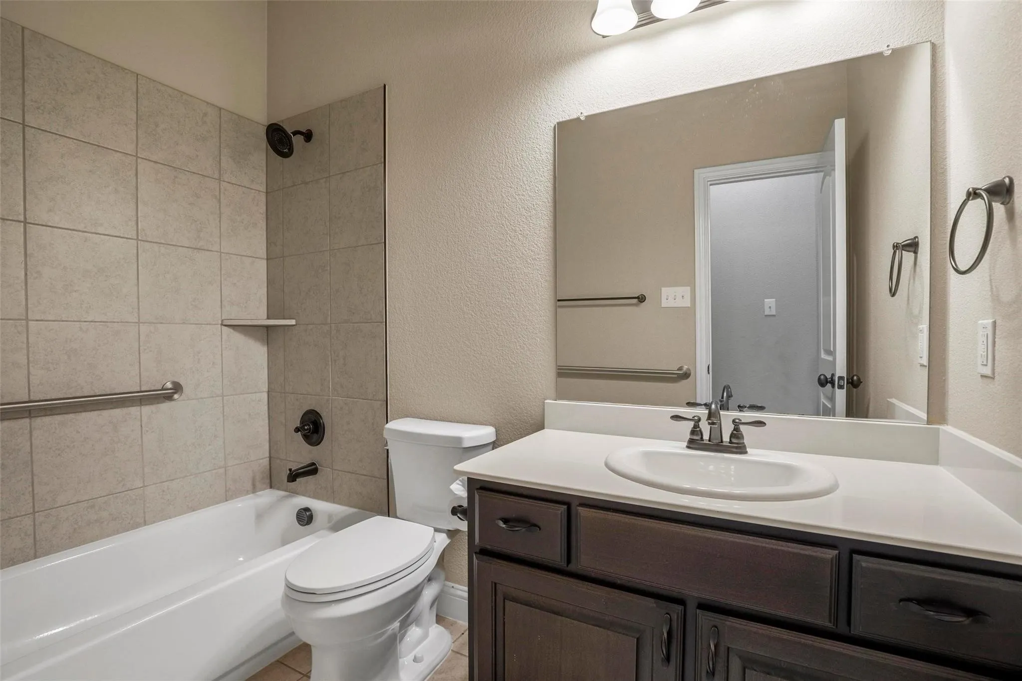 Bathroom featuring a vanity with dark-finish cabinetry, light-toned countertop, integrated basin, and brushed-finish fixtures