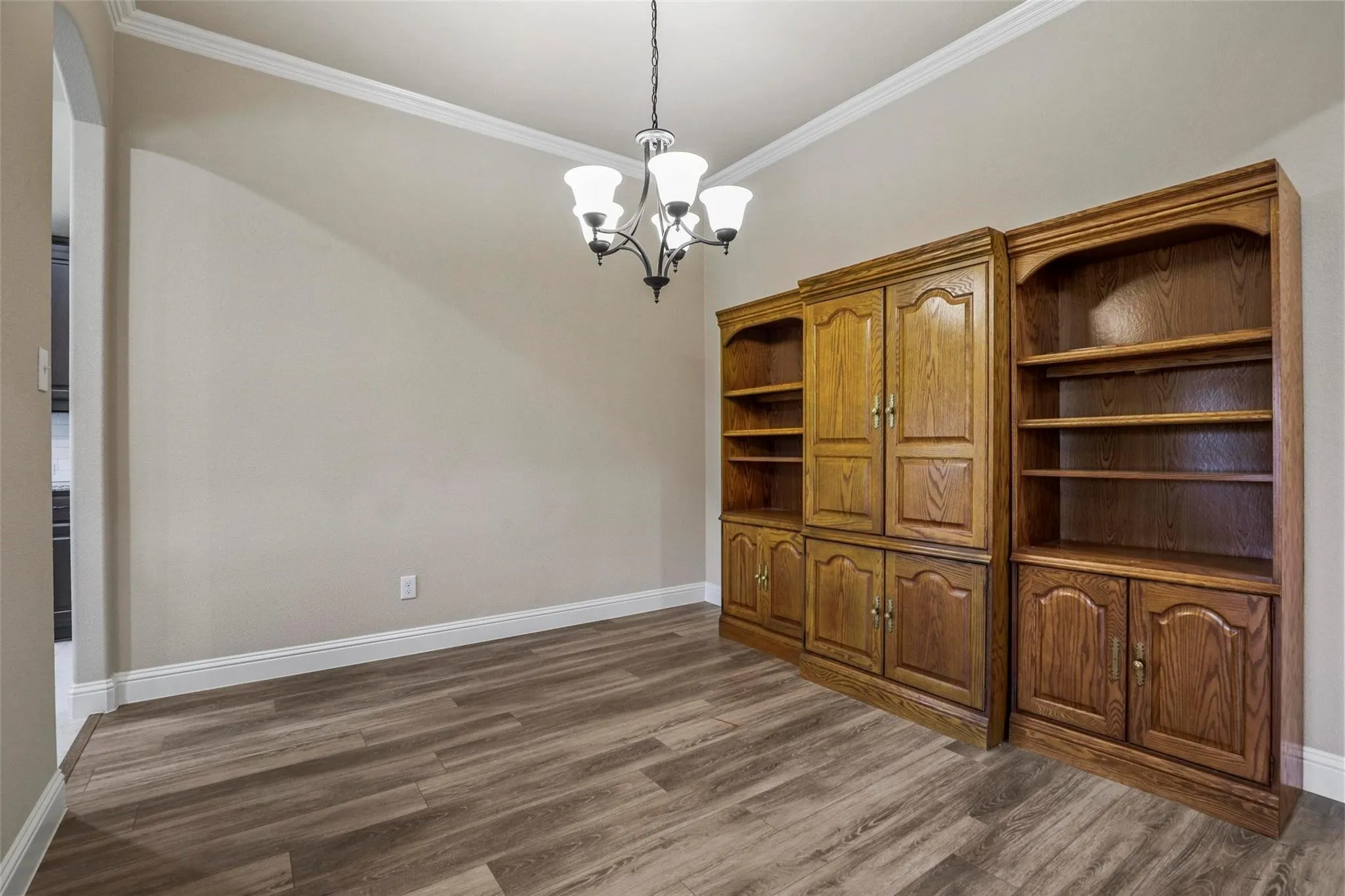 Built-in wood cabinetry with storage shelving, wood-finish flooring, and a multi-arm chandelier with glass shades