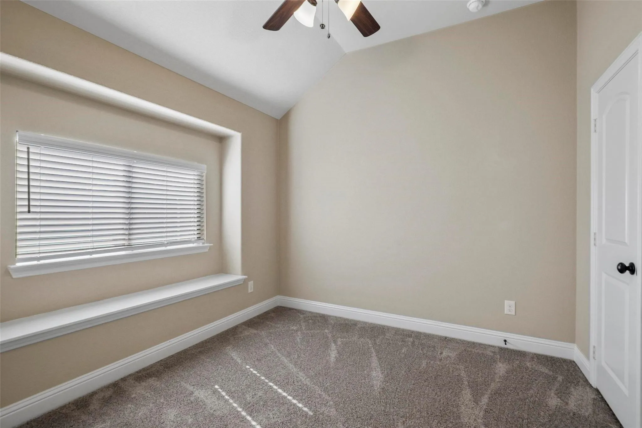 Vaulted ceiling with an overhead fan, built-in window seat, and wall-to-wall carpeting