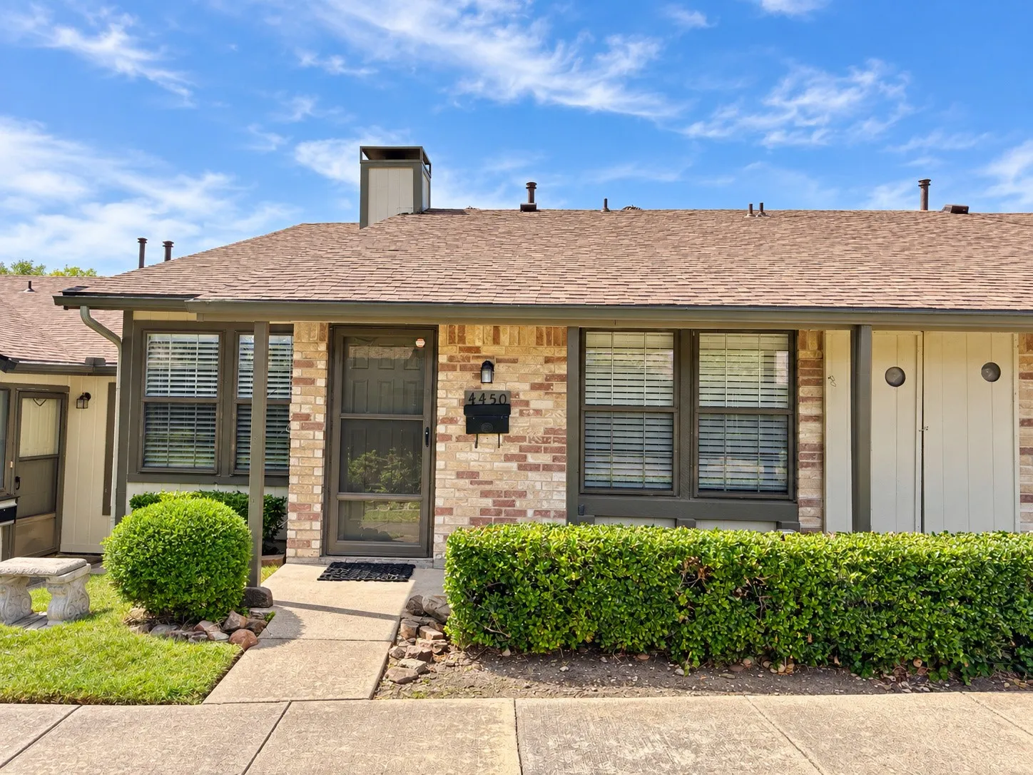 Exterior façade featuring a brick veneer finish, gabled roofline, multi-pane windows with trim, and built-in exterior storage cabinetry