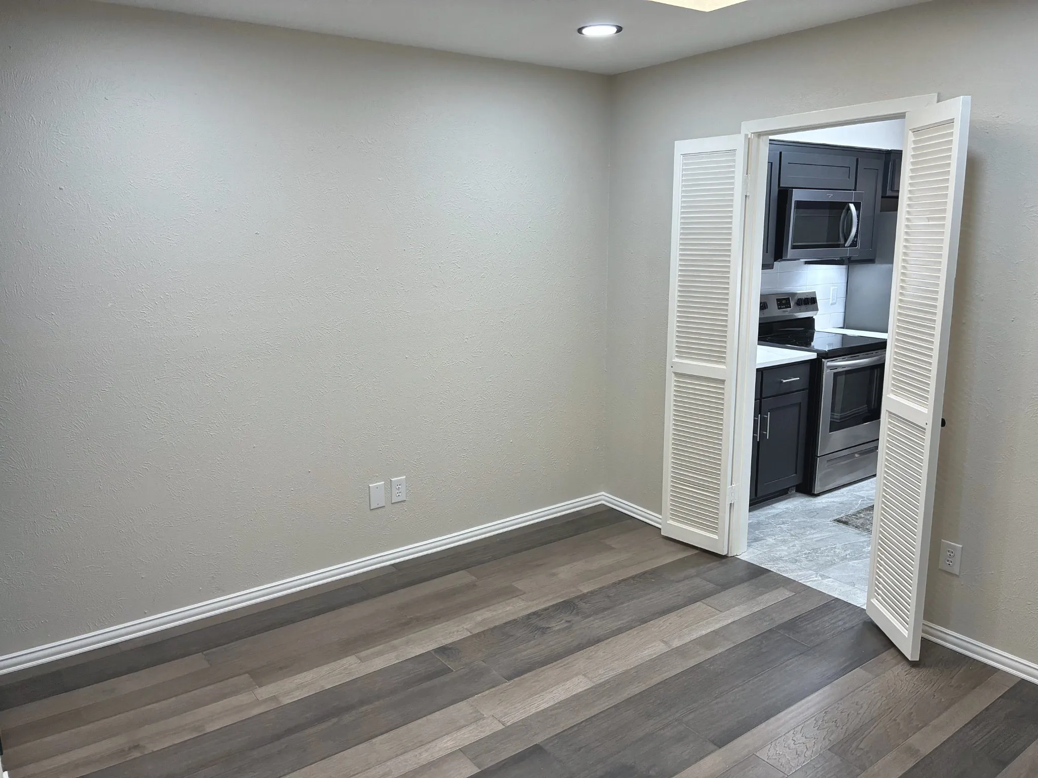 Room featuring wood-finish flooring, recessed lighting, and white louvered double doors