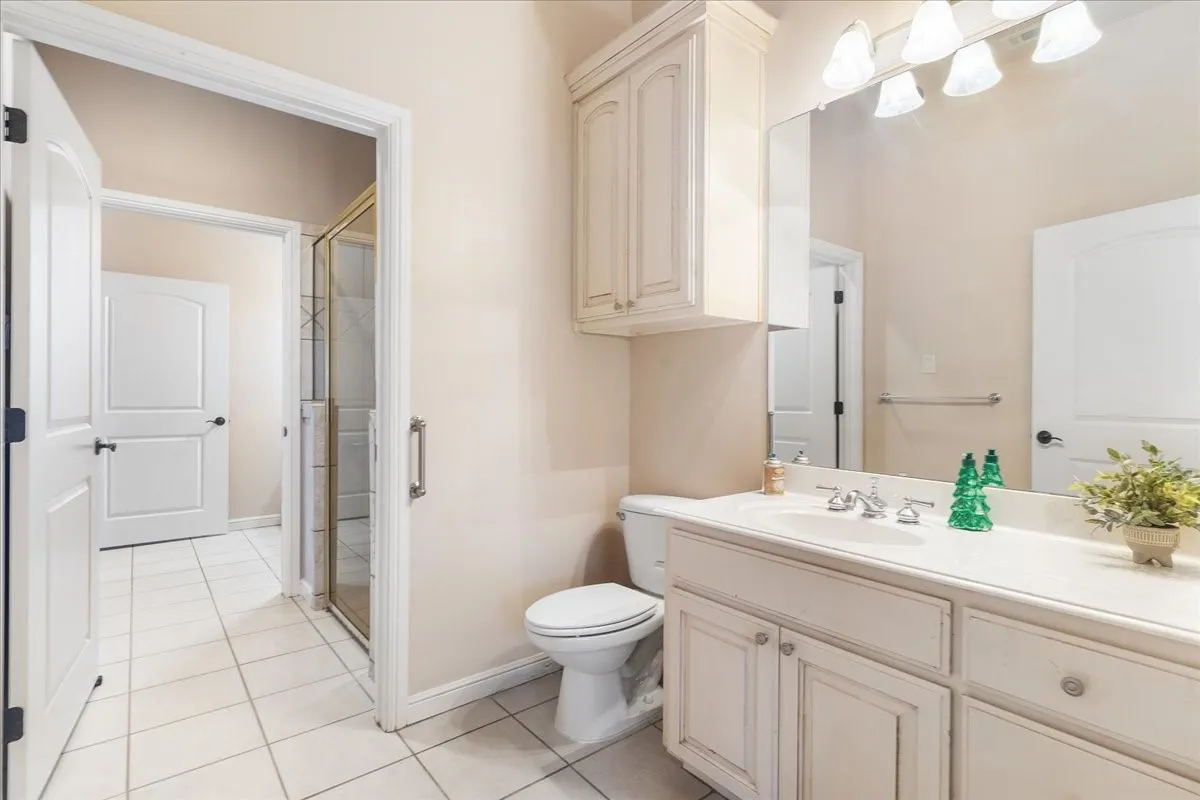 Bathroom featuring a vanity with integrated cabinetry, an expansive wall-mounted mirror, overhead multi-bulb lighting, and tile flooring