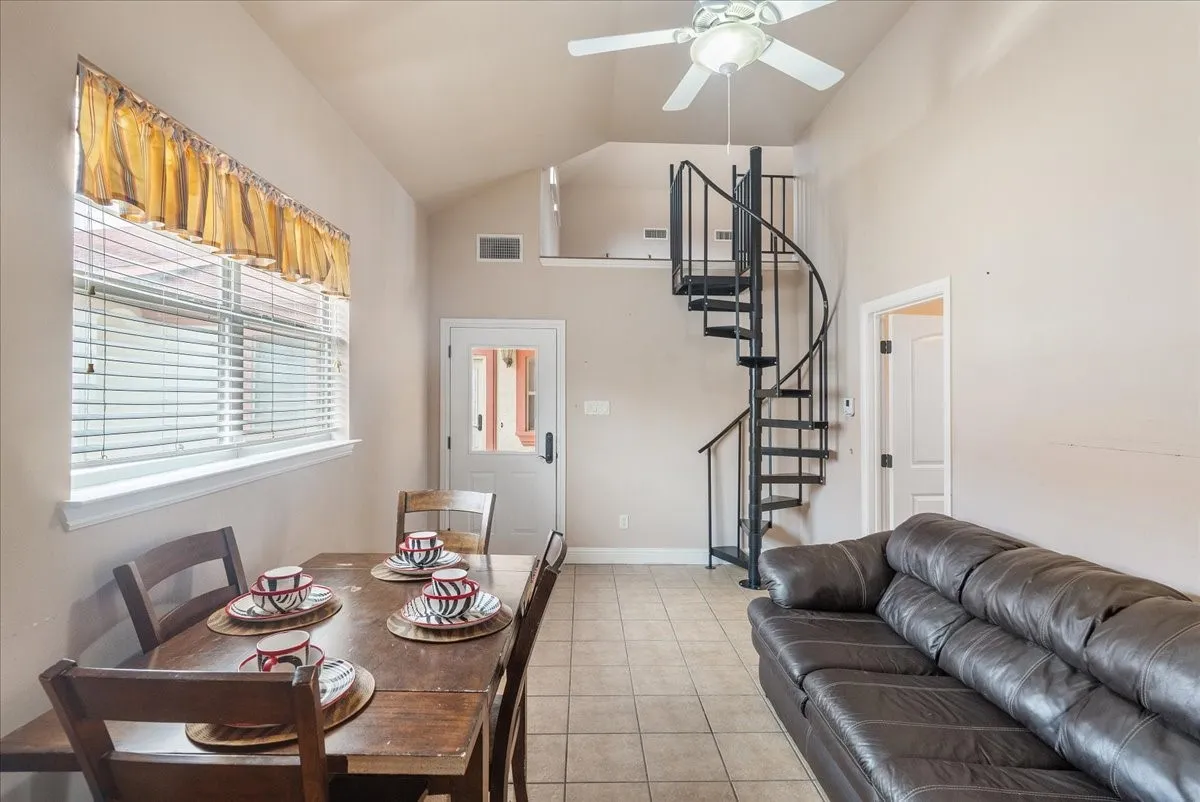 Guest House. Vaulted ceilings with ceiling fan, tile flooring, and a black spiral staircase