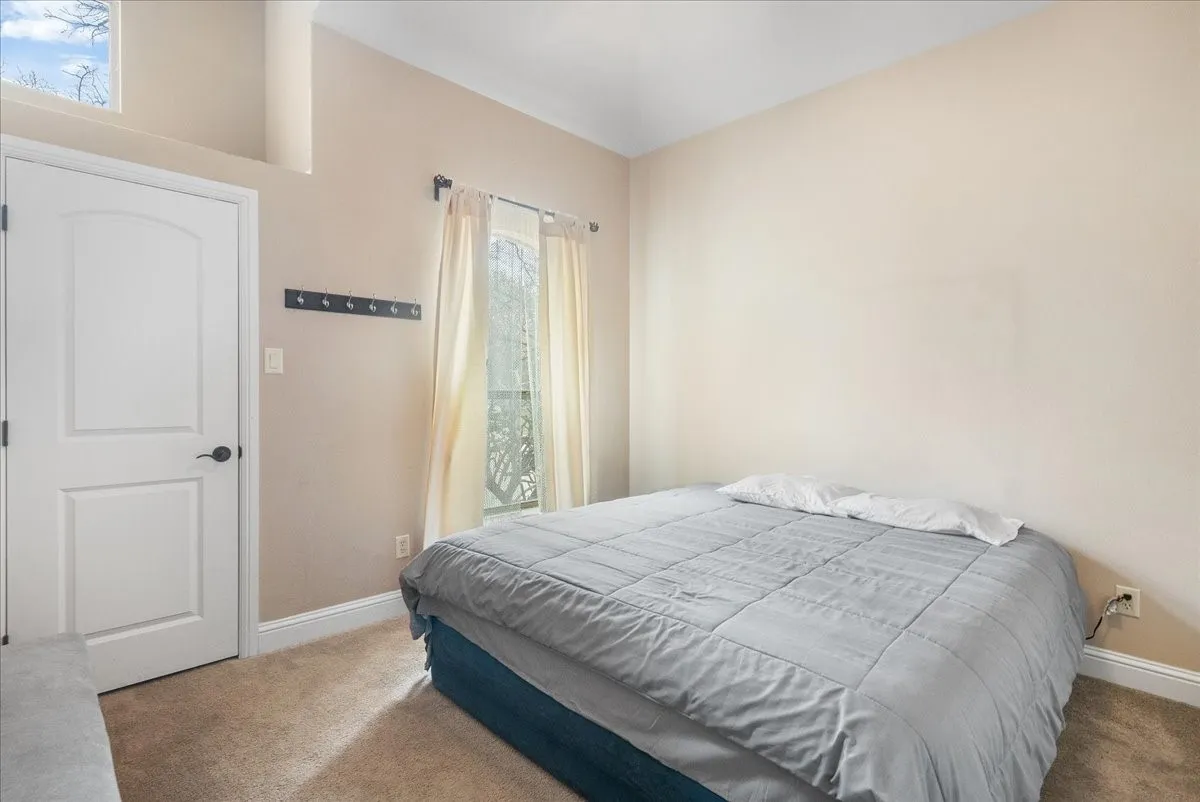 Guest House. Arched panel interior door, neutral carpeting, and a window with natural light