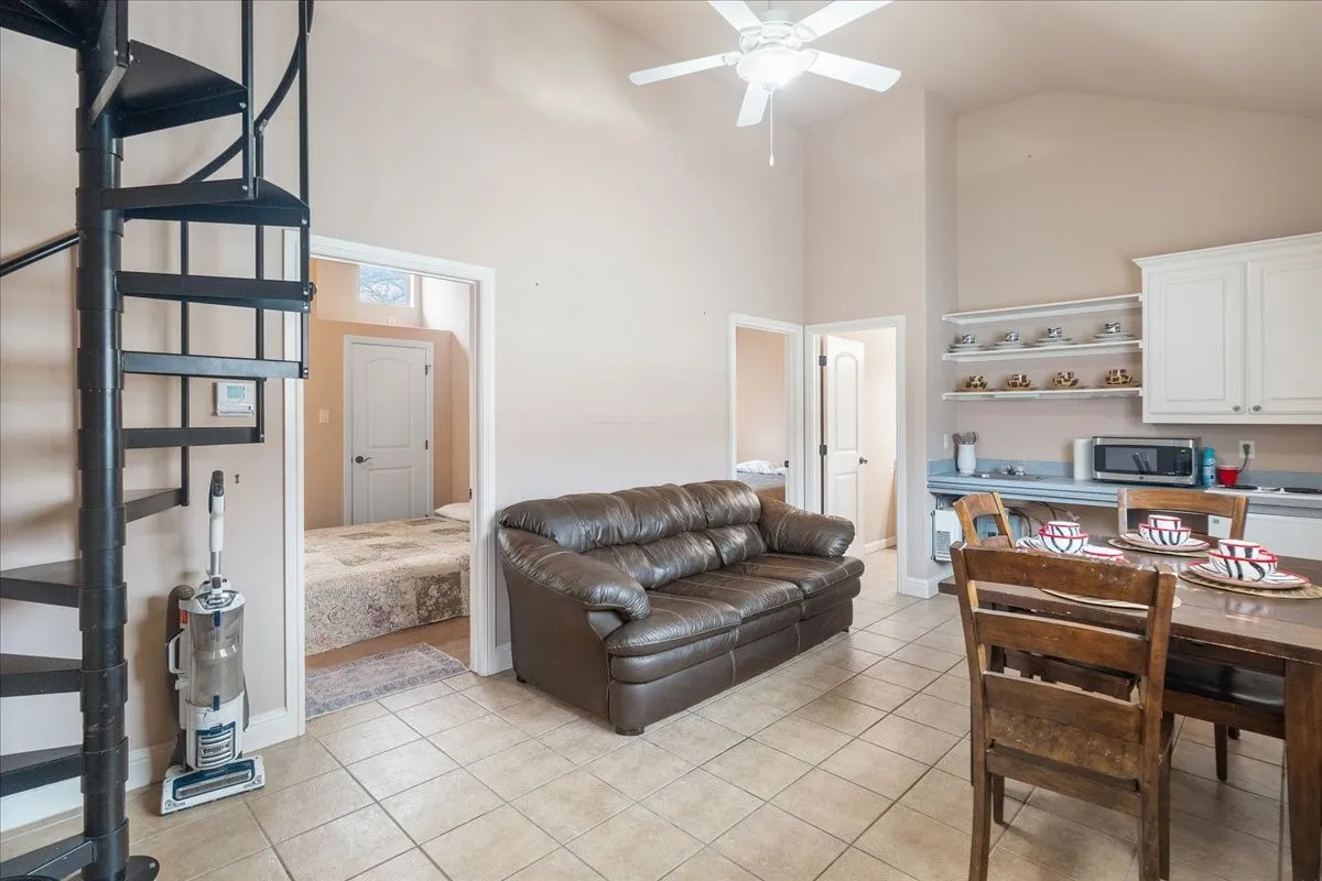Entrance to guest house, black metal spiral staircase, tile flooring, built-in white cabinetry, and open shelving