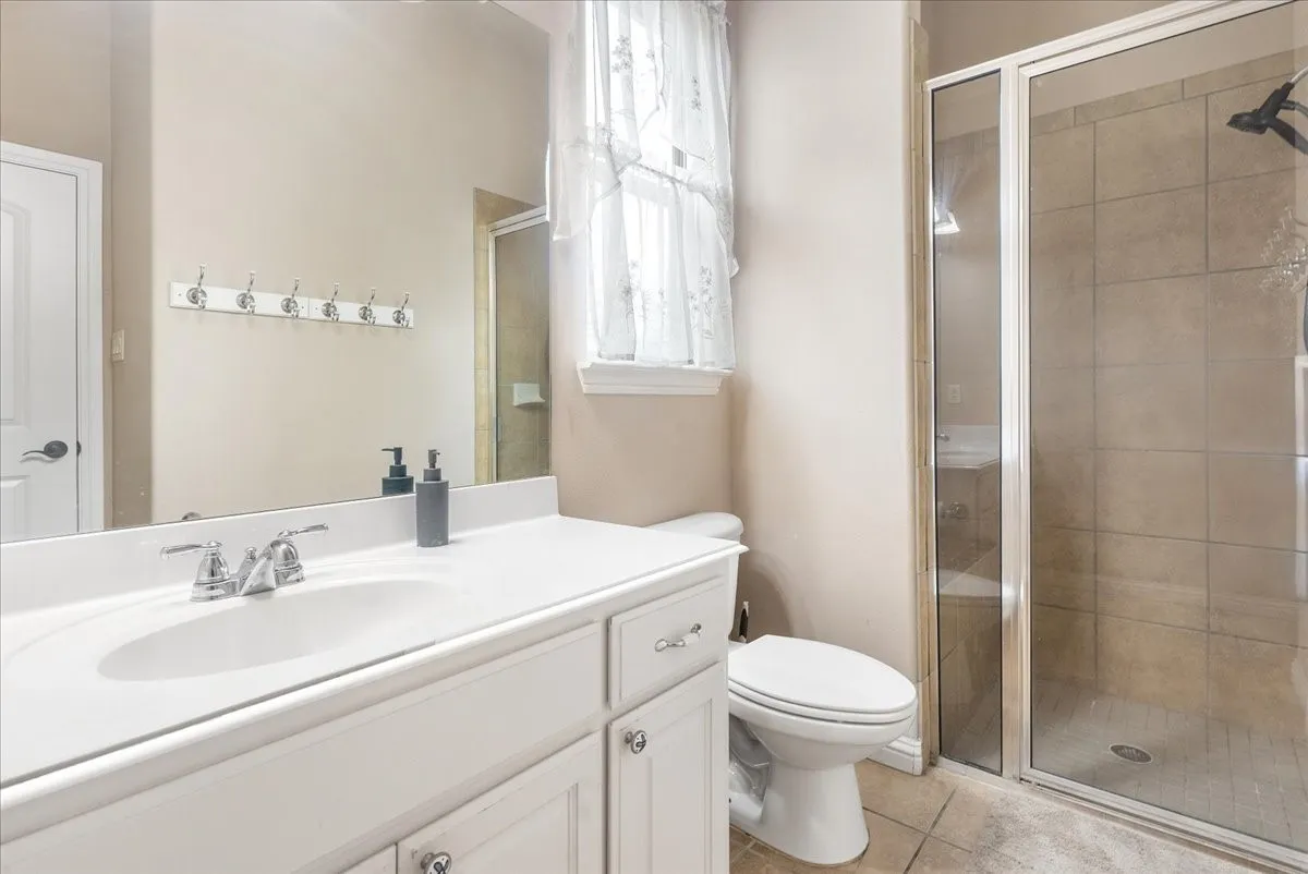 Guest house. Bathroom Spa-inspired bathroom featuring a white vanity with ample counter space, ceramic sink, chrome fixtures, and recessed lighting above the mirror