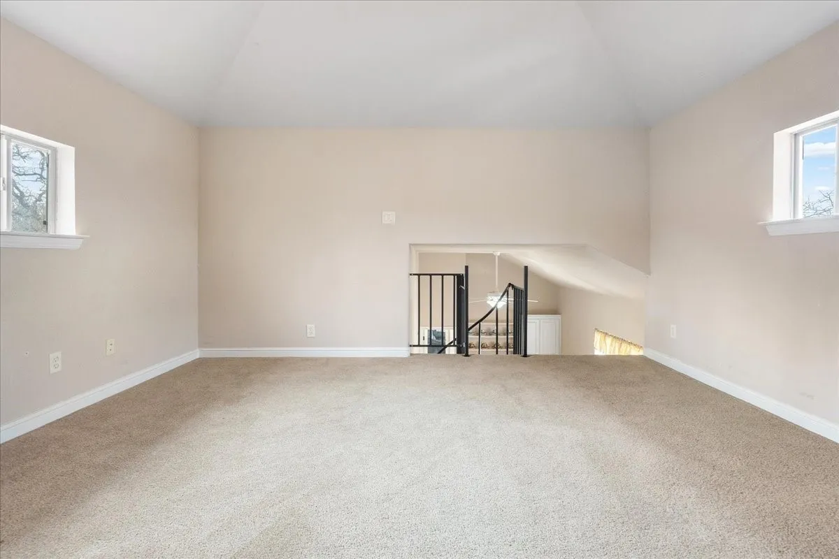 Guest house.Carpeted open loft space with vaulted ceiling and multiple windows