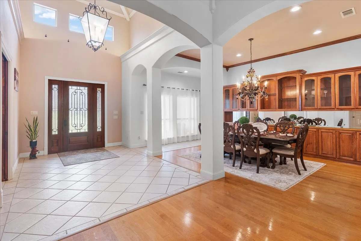 Foyer featuring high ceilings, natural wood-finish flooring, diamond-patterned tile, arched architectural detailing, and a decorative lantern-style chandelier