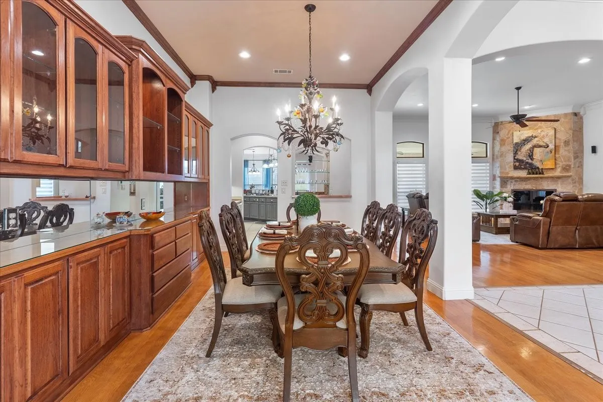 Formal dining area featuring extensive built-in wood cabinetry, a mirrored backsplash, recessed lighting, and an ornate wrought-iron chandelier