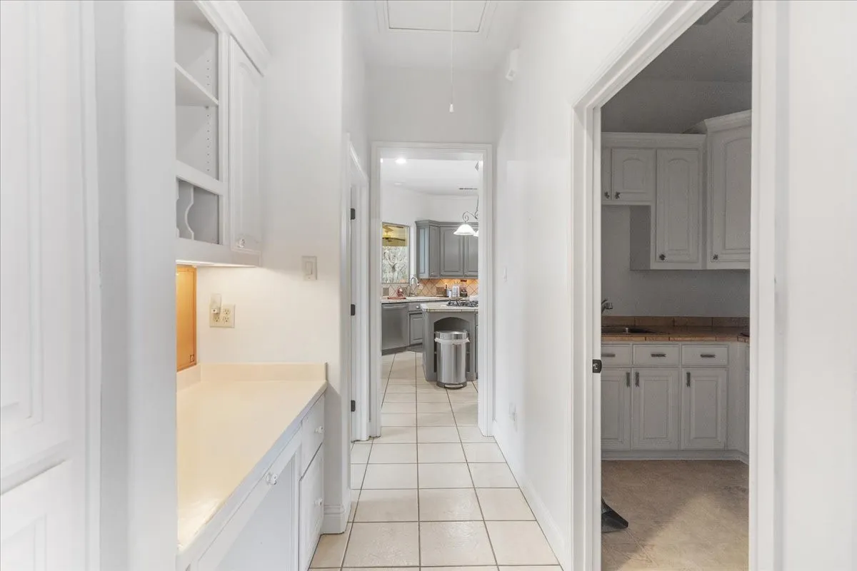 Hallway featuring tile flooring and built-in cabinetry with under-cabinet lighting