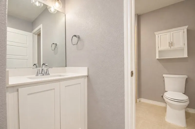 White vanity with integrated sink, chrome faucet, and overhead lighting