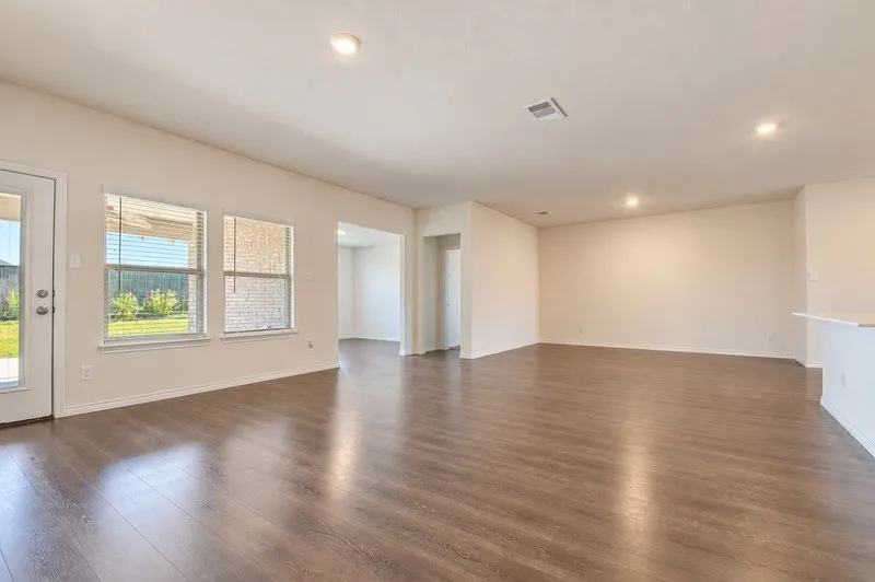 Spacious room featuring wood-finish flooring, recessed lighting, multiple windows, and a built-in breakfast bar
