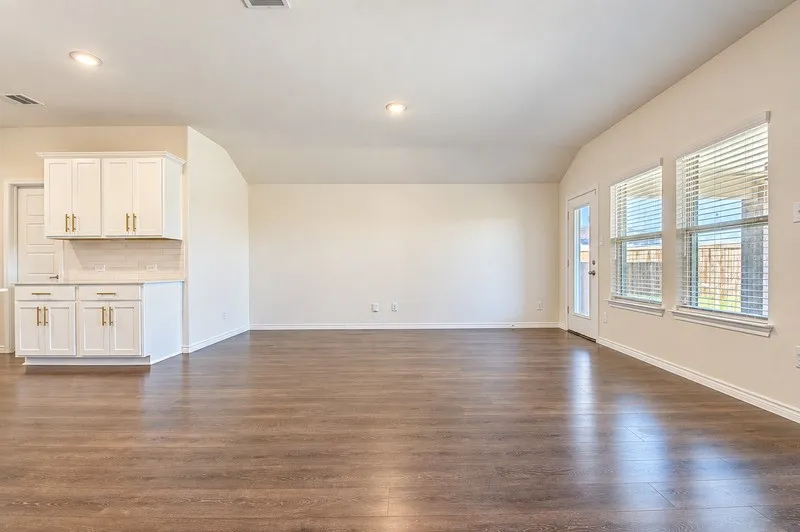 Spacious interior with wood-finish flooring, white cabinetry with gold-tone hardware, and a glass-paned door