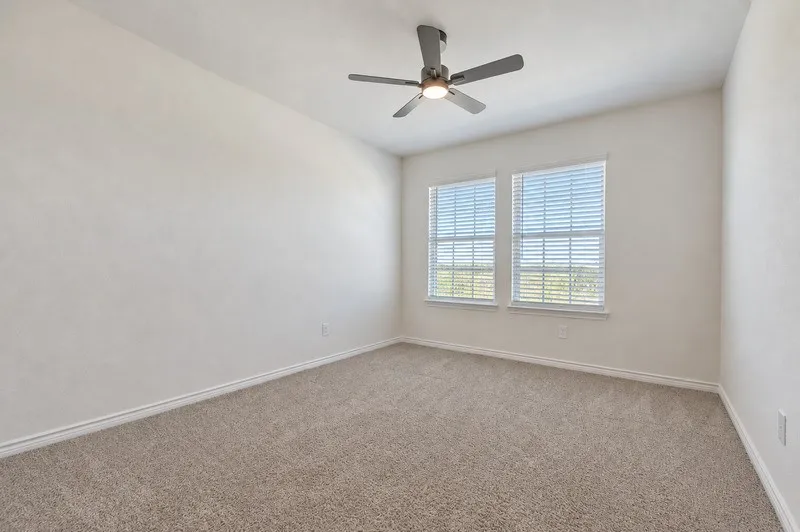 Carpeted flooring, ceiling fan with integrated lighting, and dual windows with blinds