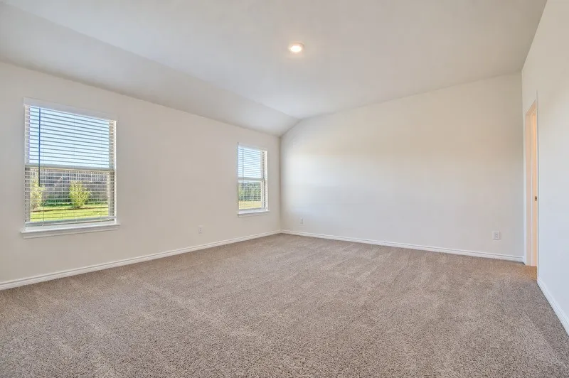Spacious room featuring vaulted ceilings, recessed lighting, neutral-toned carpeting, and multiple windows