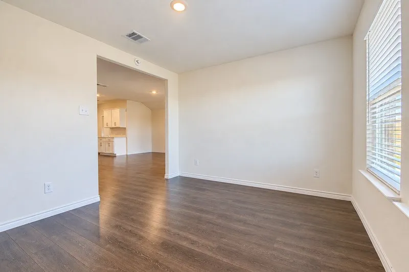 Wood-finish flooring throughout, recessed ceiling lighting, light-colored wall paint, white trim, and a window with blinds
