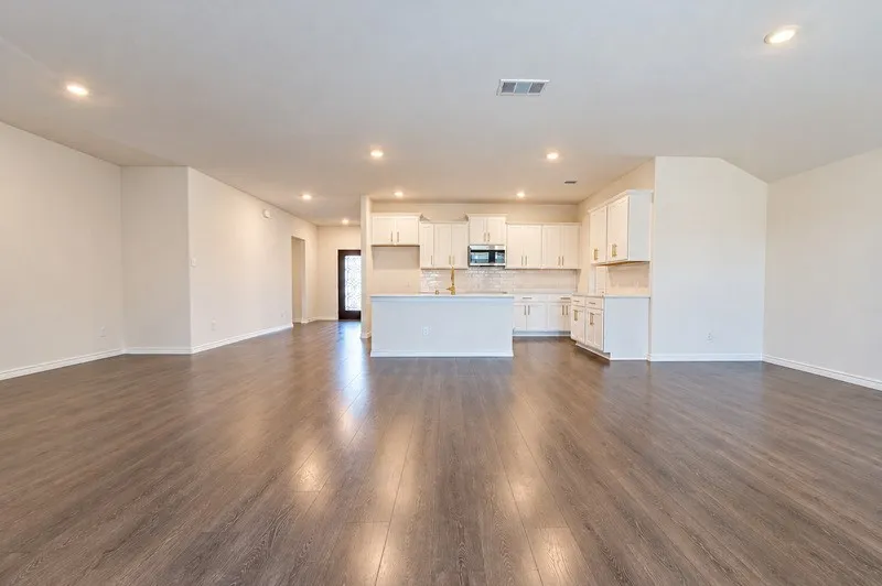 Open-concept living space featuring wood-finish flooring, recessed lighting, and a kitchen with white cabinetry, a central island, and a tile backsplash