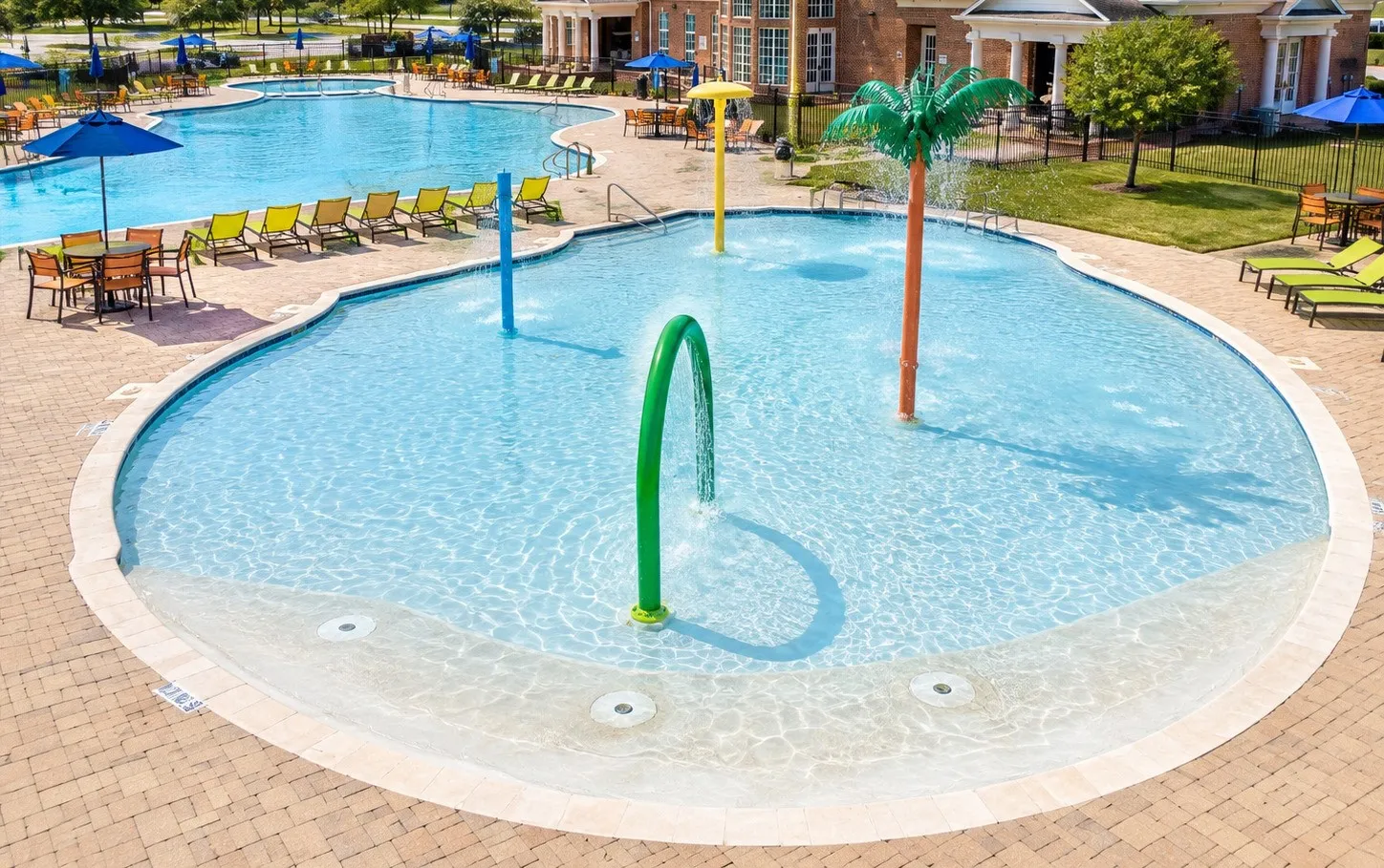 Large swimming pool with a connected splash pad area featuring multiple water spray elements