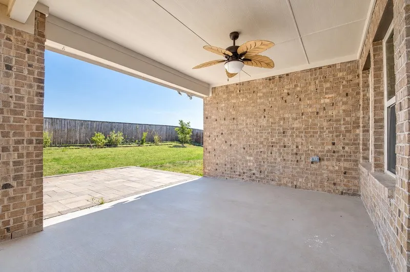 Covered patio with a ceiling fan, concrete flooring, and brick construction