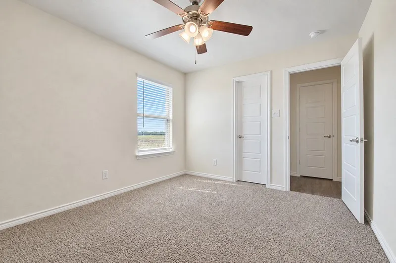 Plush carpet flooring, ceiling fan with light fixture, window with blinds, and white paneled doors