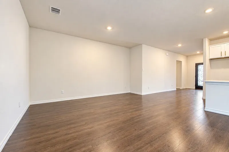 Spacious room featuring wood-finish flooring, recessed lighting, and crisp white walls