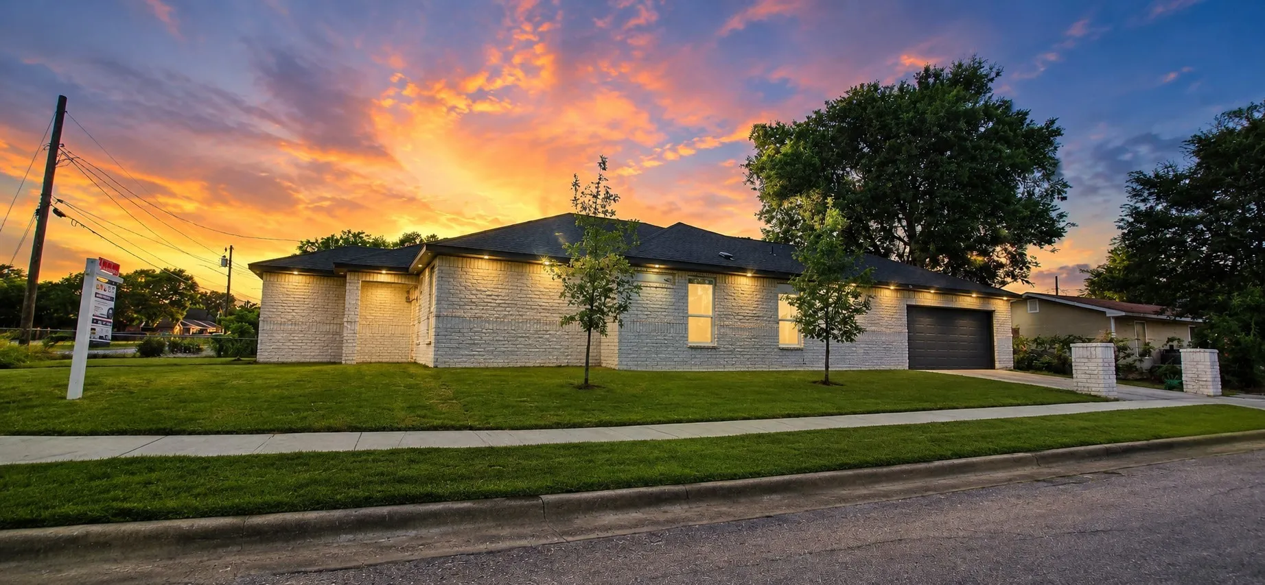 Single-story residence featuring a painted brick exterior, recessed soffit lighting, an attached garage, and a manicured lawn