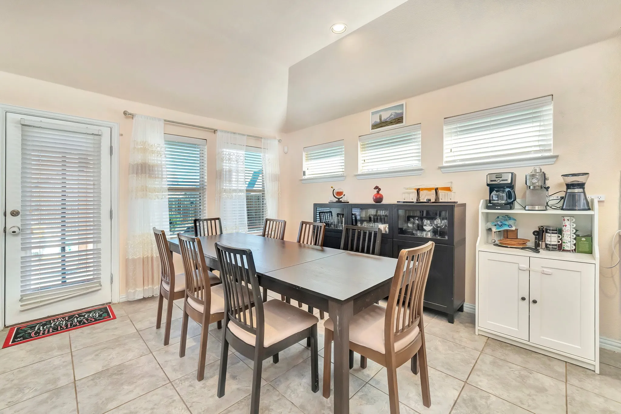 Vaulted ceilings, large-format tile flooring, abundant natural light via multiple windows, and a glass-paneled exterior door