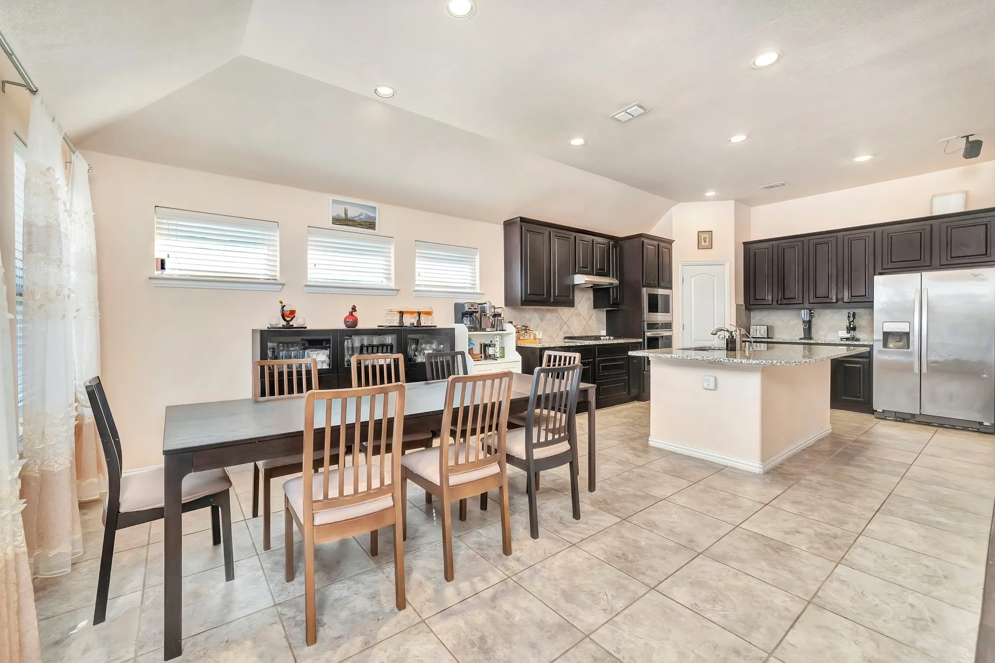 Open kitchen featuring dark cabinetry, stone-finish countertops, stainless steel appliances, a central island, and recessed lighting throughout