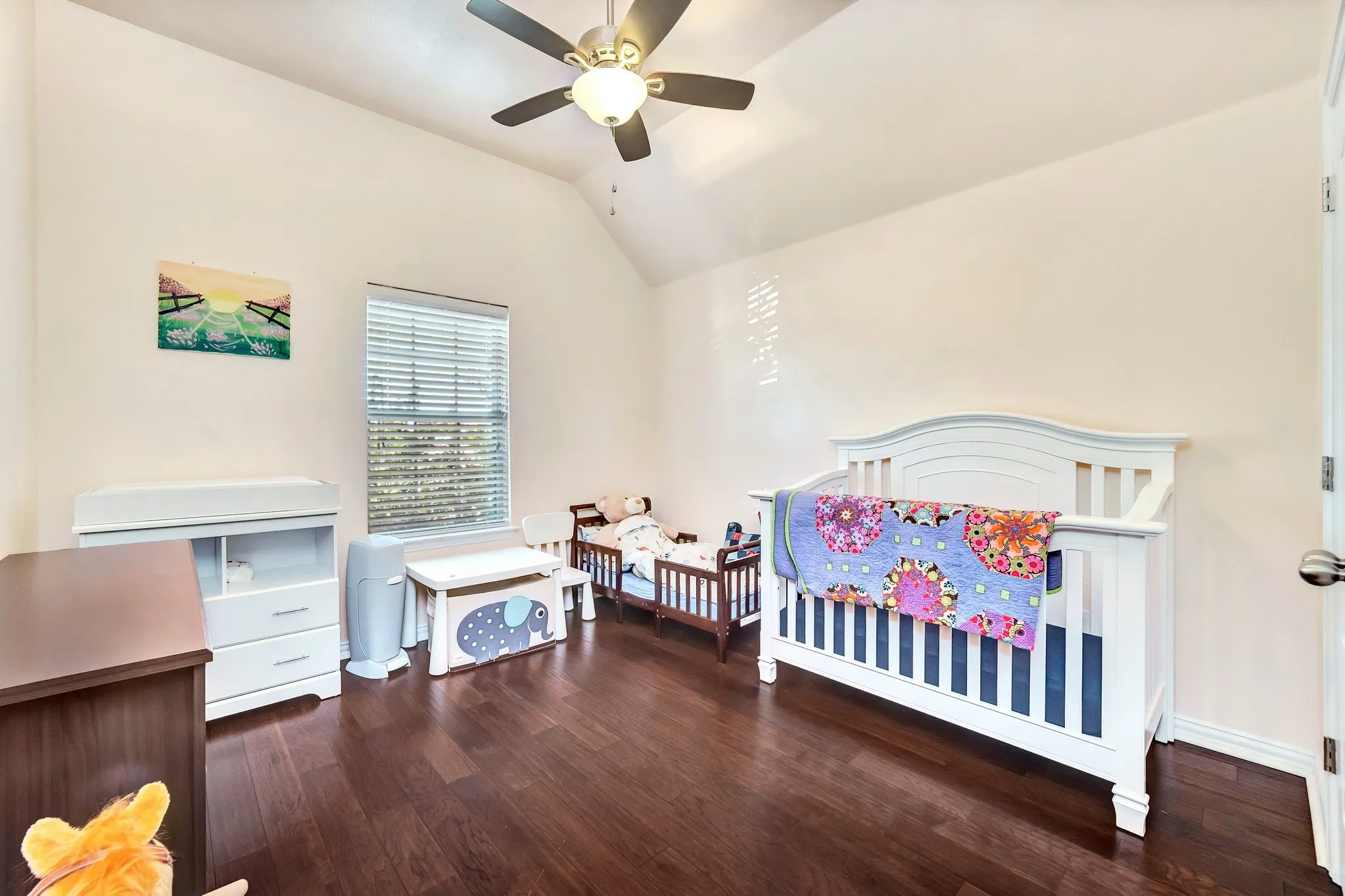 Room featuring vaulted ceilings, dark wood-finish flooring, and a ceiling fan with integrated lighting