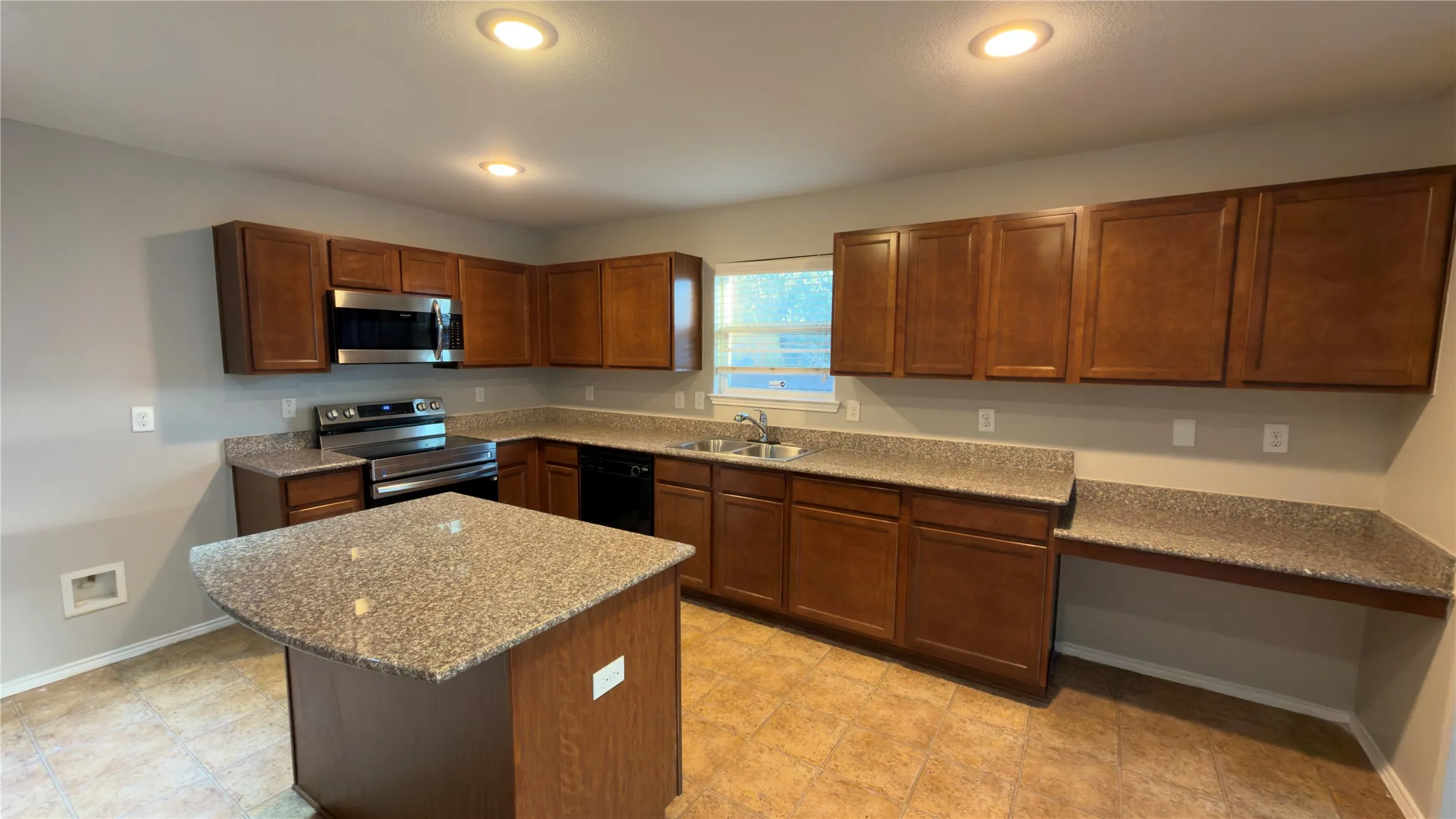 Kitchen featuring wood cabinetry, stone-finish countertops, a central island, integrated stainless steel appliances, and recessed ceiling lighting