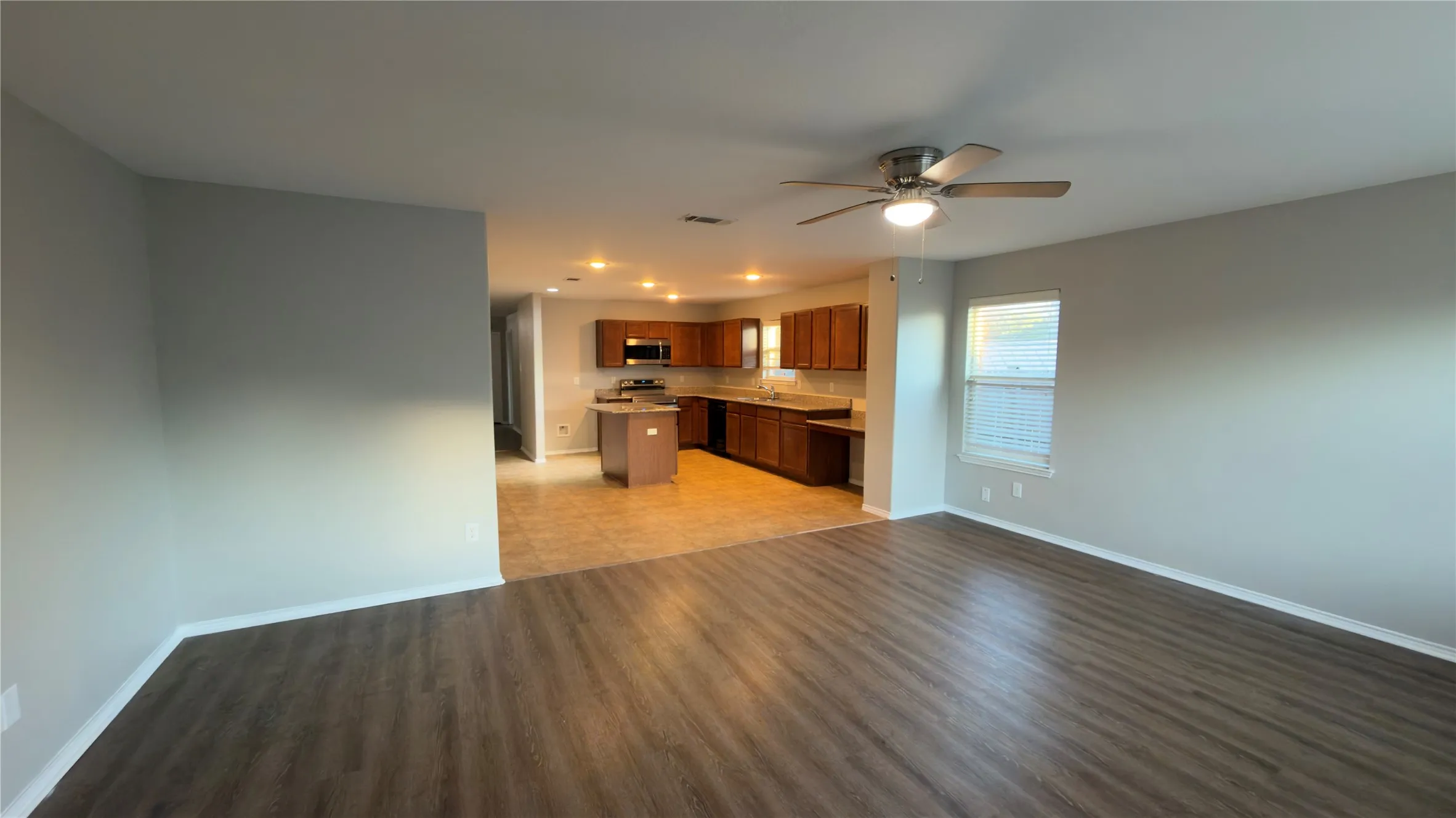 Open-concept interior featuring wood-finish flooring, a kitchen island, recessed ceiling lighting, and a ceiling fan