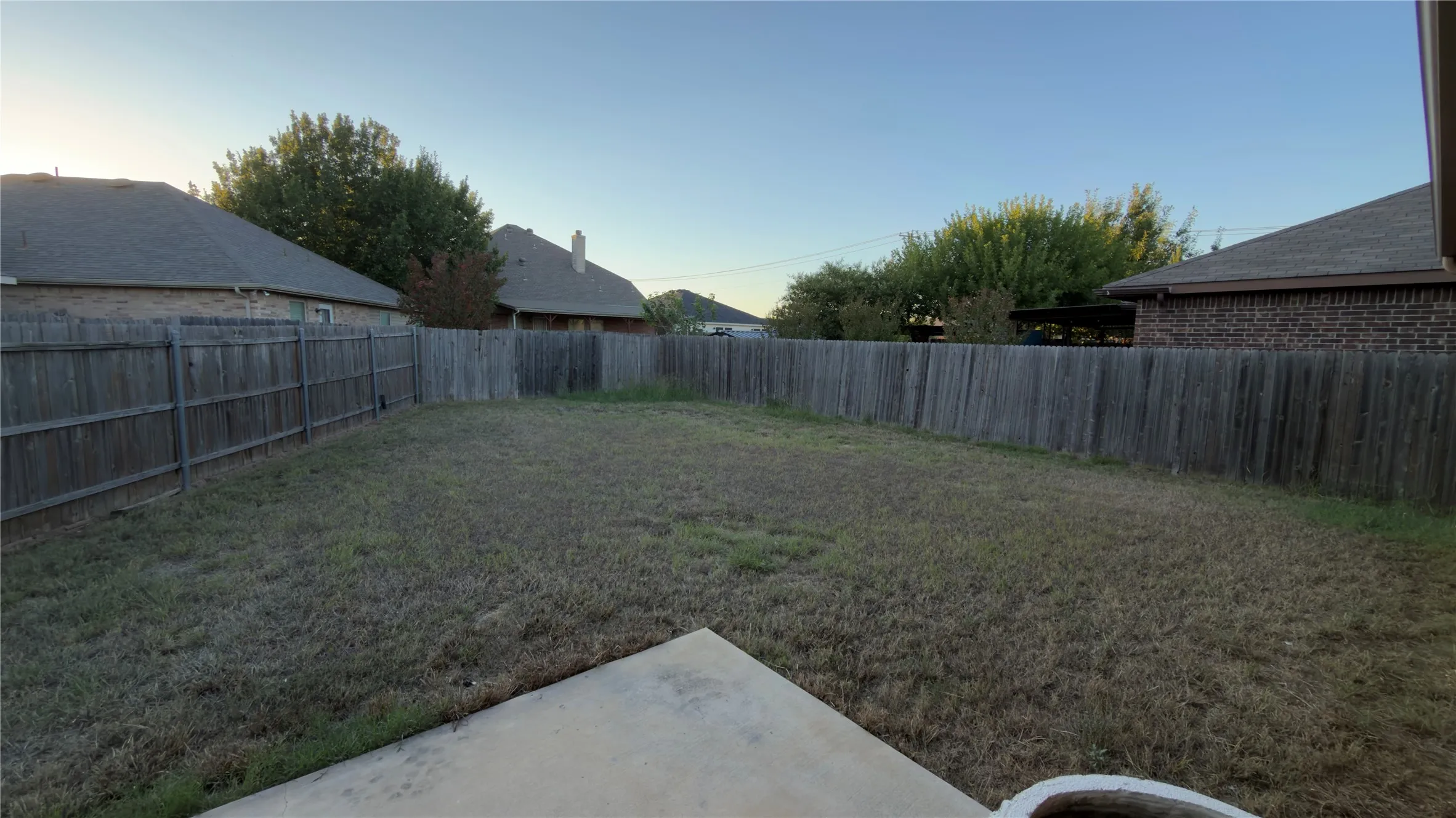 Backyard featuring a concrete patio, wood privacy fencing, and open lawn space