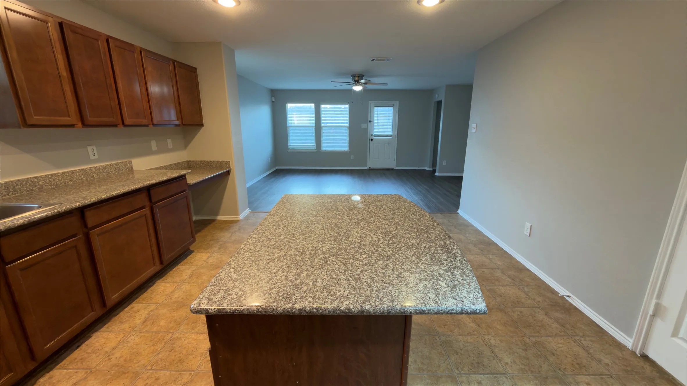 Kitchen featuring wood cabinetry, stone-surface countertops, central island, and recessed lighting
