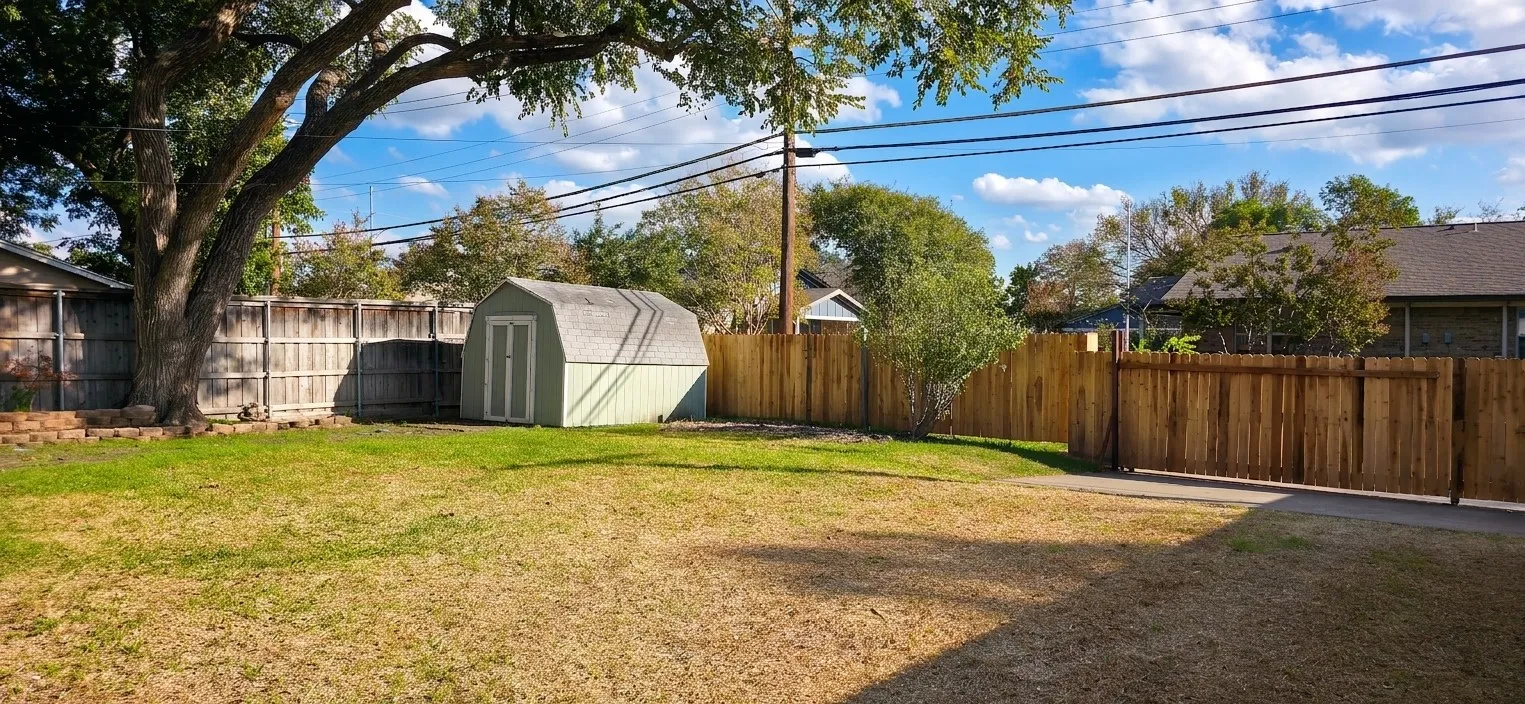 Rear yard featuring a grass lawn, perimeter wood fencing, a detached storage shed, and a mature tree