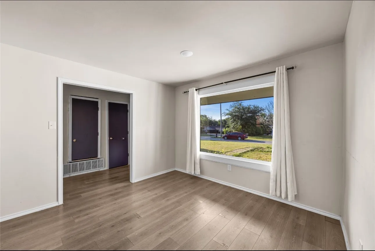 Room featuring wood-finish flooring, a large picture window, and neutral wall paint