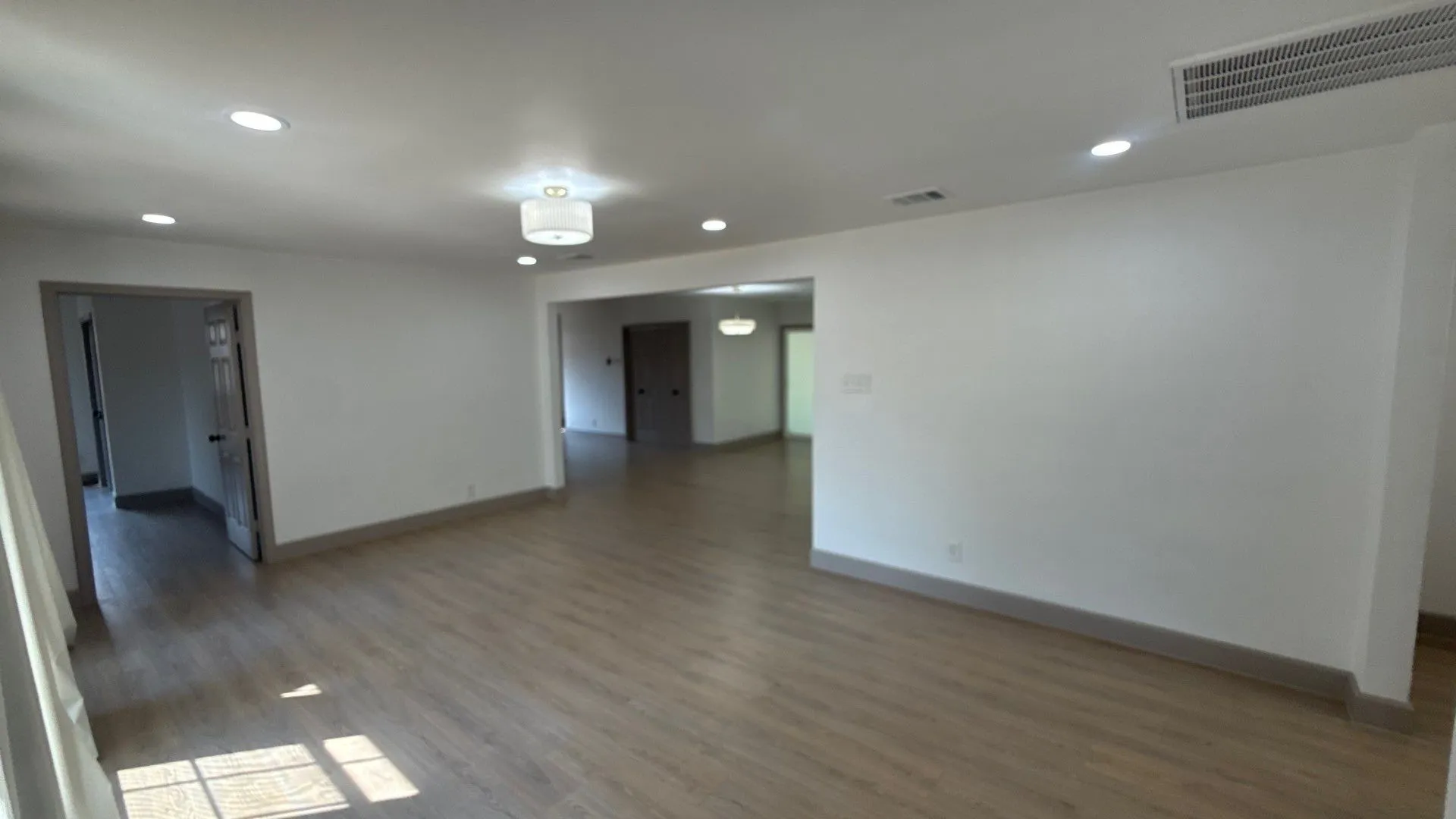 Neutral wall paint, wood-finish flooring, recessed lighting, and multi-light ceiling fixtures