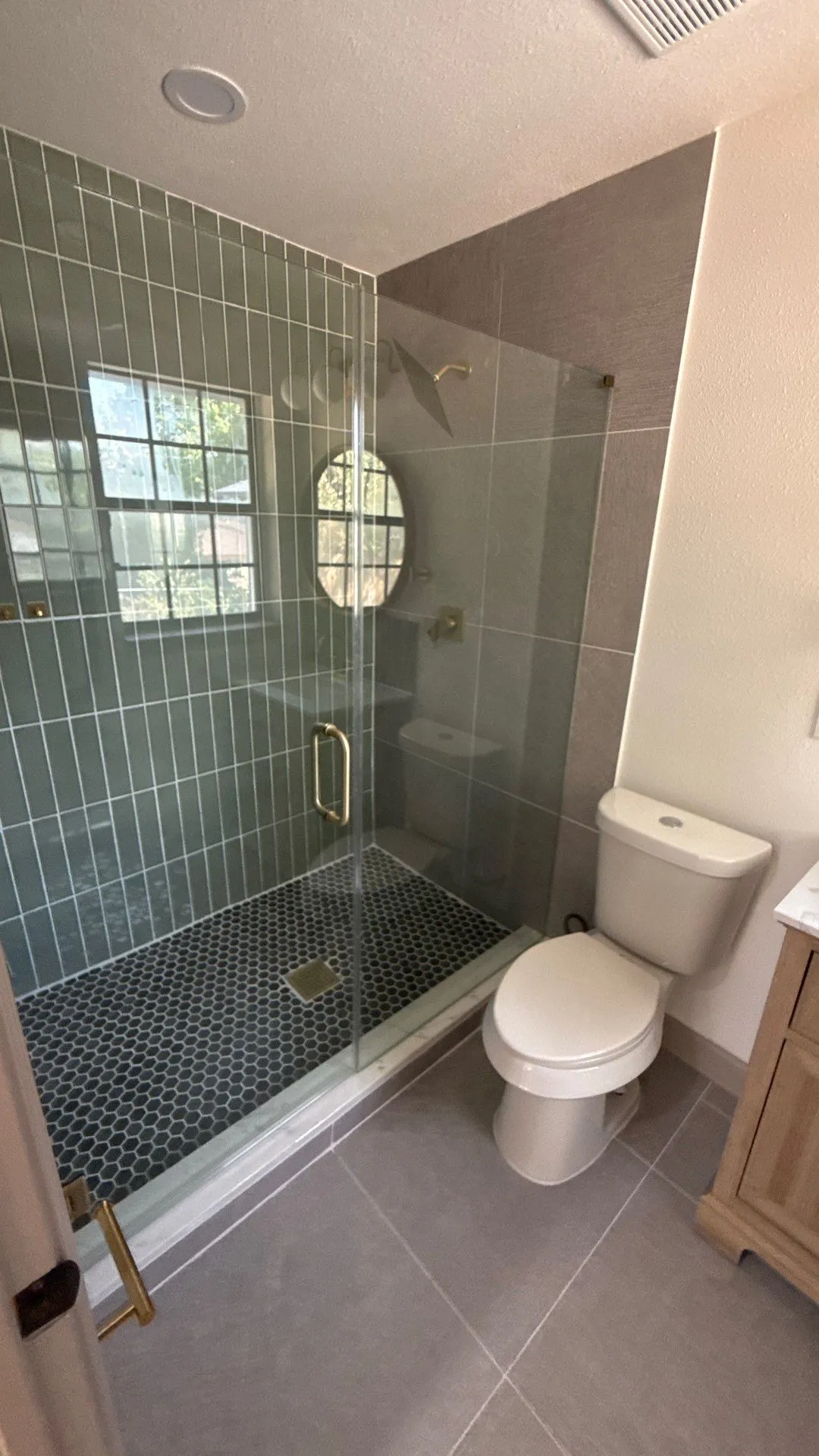 Walk-in shower featuring vertical tile walls, glass enclosure, and penny-round tile flooring