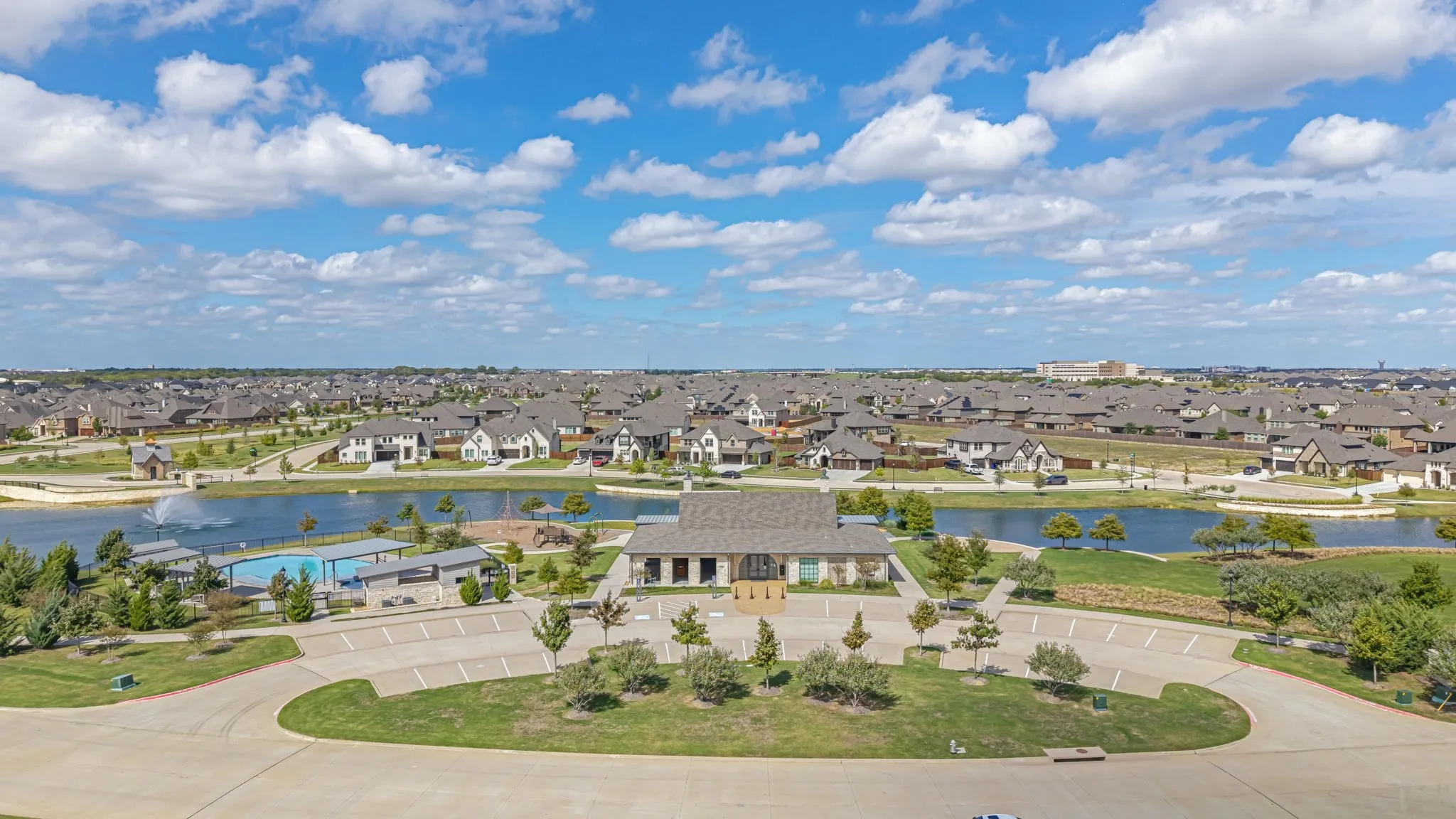 Community amenity center featuring a swimming pool, clubhouse, water feature, and dedicated parking