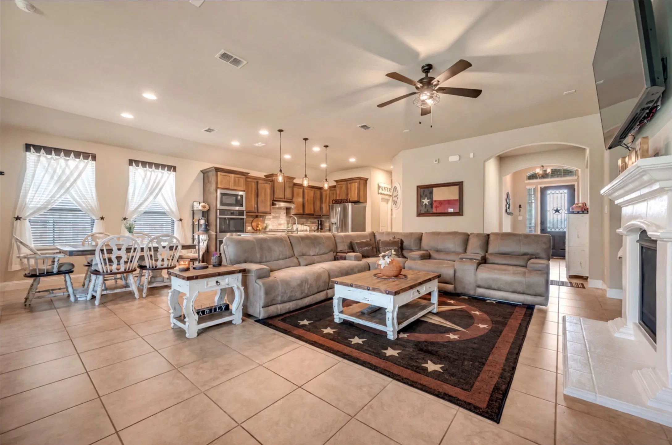 Open-concept floor plan featuring ceramic tile flooring, recessed lighting, and a white mantle fireplace