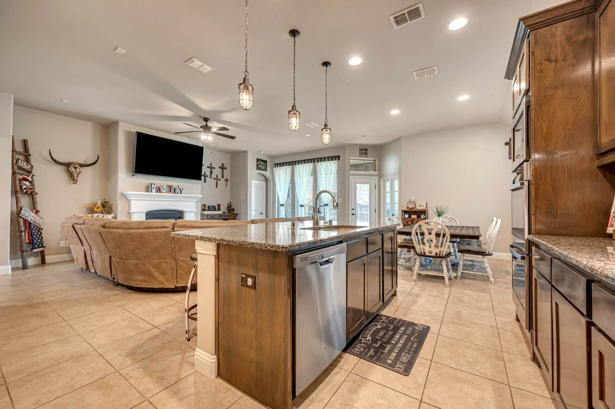 Kitchen featuring stone-surface countertops, wood-finish cabinetry, stainless steel dishwasher, recessed lighting, and trio of pendant​​‌​​​​‌​​‌‌​‌‌​​​‌‌​‌​‌​‌​​​‌​​ lights