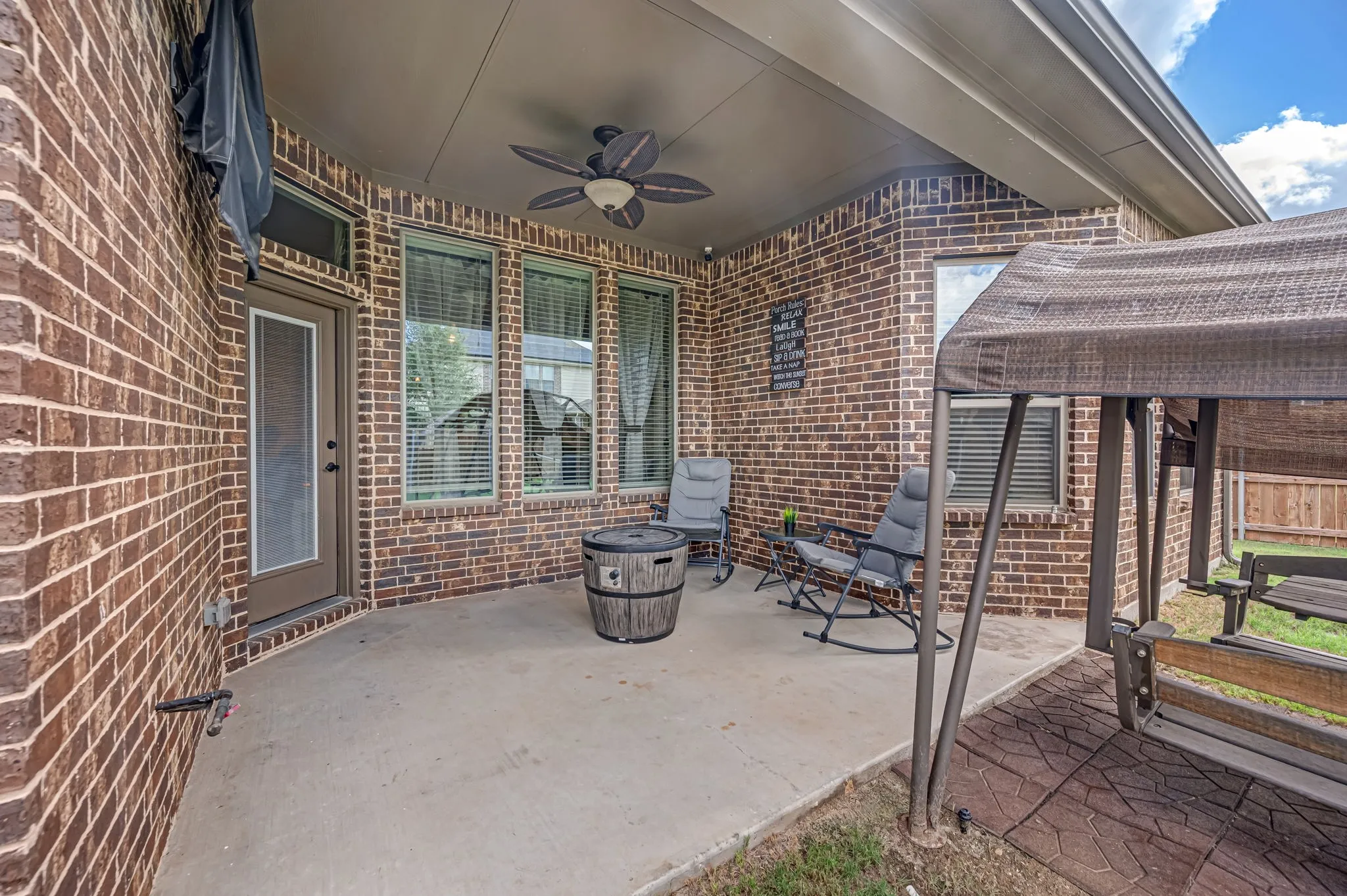 Covered brick patio featuring a concrete floor, a ceiling-mounted fan, and multiple tall windows