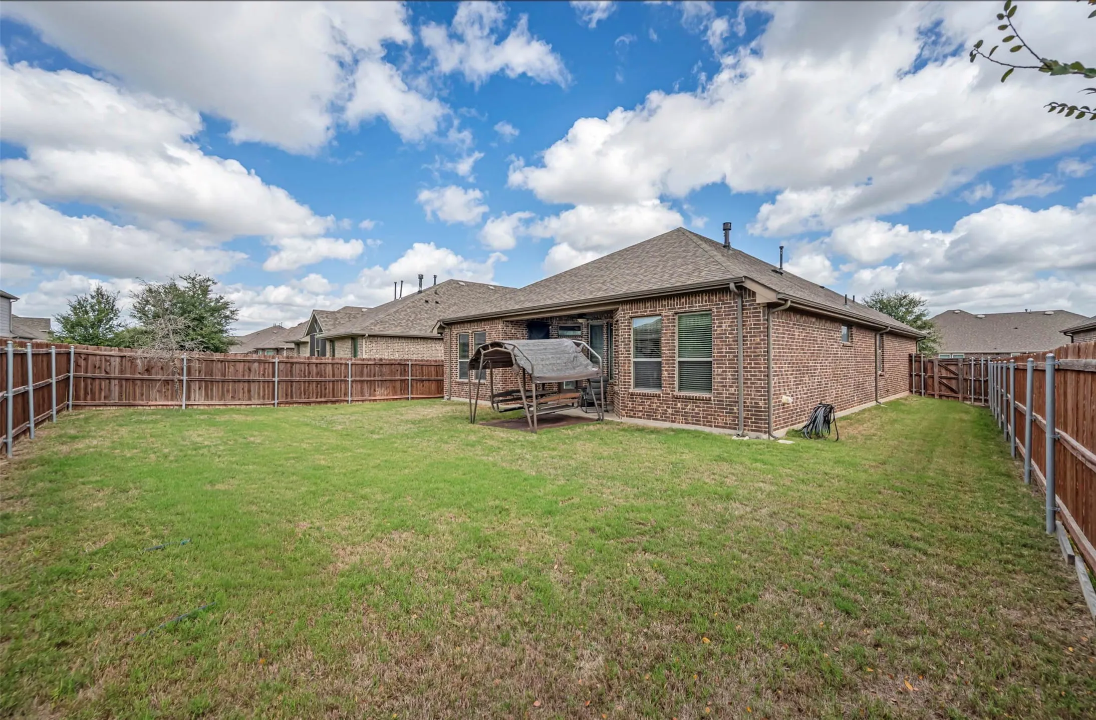 Private rear yard featuring a brick exterior facade, grass lawn, and wood privacy fencing
