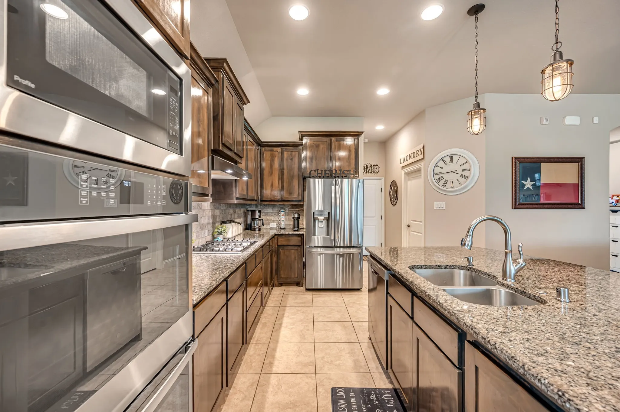 Kitchen featuring stained wood cabinetry, stone-surface countertops, built-in stainless steel double ovens, stainless steel refrigerator, and recessed lighting