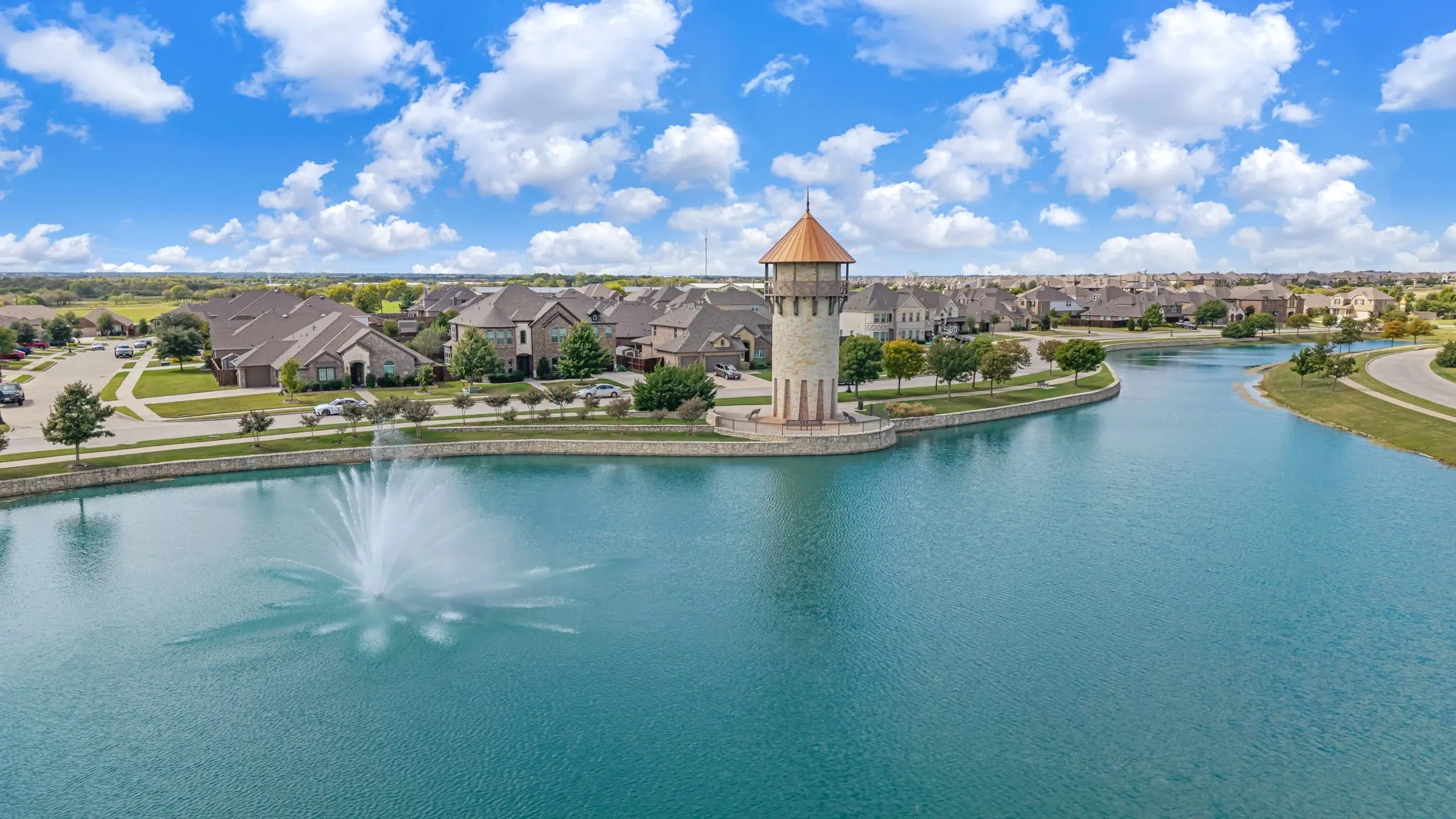 Expansive waterfront setting featuring a decorative water fountain, a stone-clad architectural tower, and stone retaining walls
