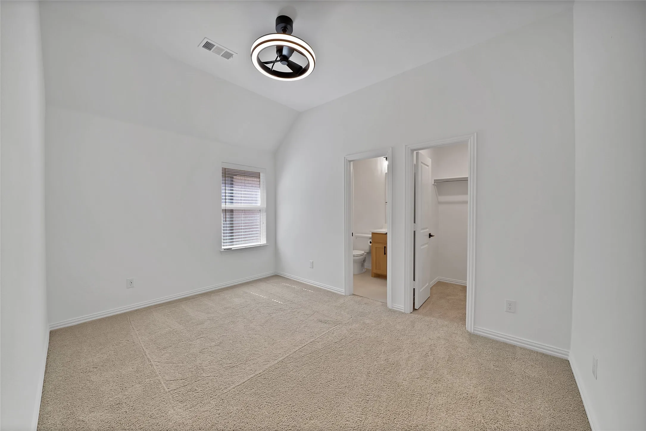 Vaulted ceiling room featuring neutral carpeting, a modern circular LED light fixture, and an integrated closet